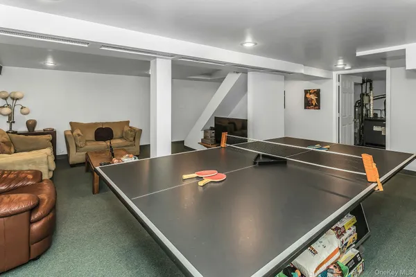 a living room with furniture pool table and stairs
