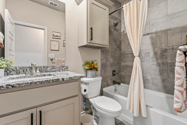a bathroom with a granite countertop toilet sink and mirror