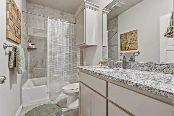 a bathroom with a granite countertop sink toilet and shower