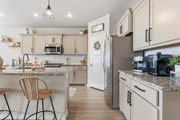 a kitchen with stainless steel appliances granite countertop a refrigerator a stove a sink a dining table and chairs