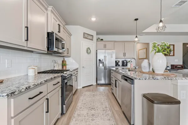 a kitchen with stainless steel appliances granite countertop a stove a sink and a refrigerator