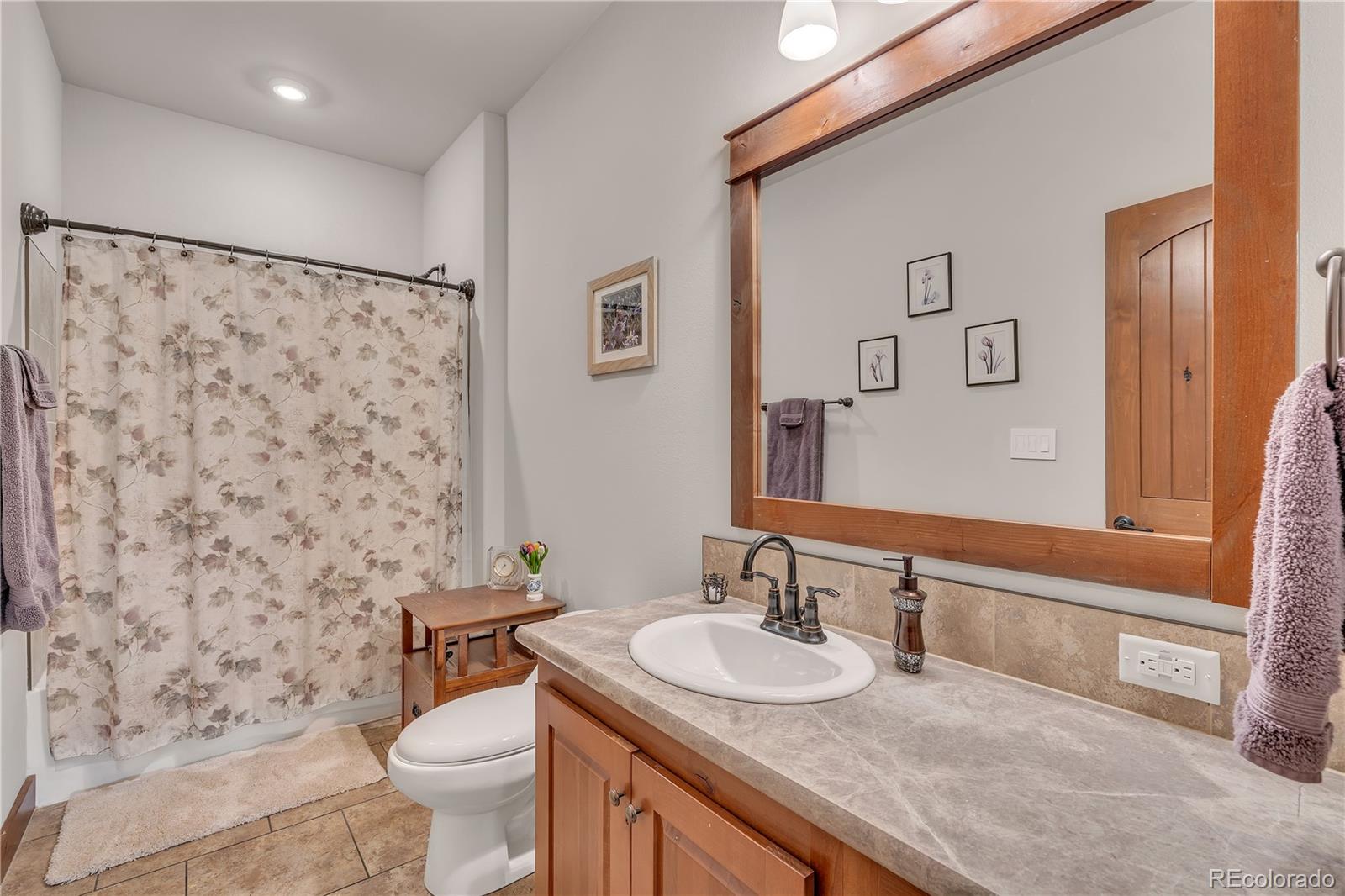 6839 Estes Drive Arvada, CO 80004 - Photo 12 of 34 a bathroom with a granite countertop sink a toilet and a mirror