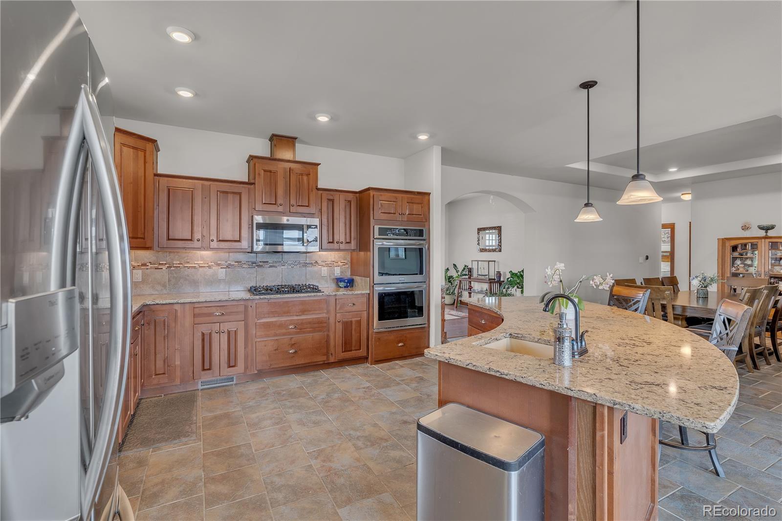 6839 Estes Drive Arvada, CO 80004 - Photo 4 of 34 a kitchen with kitchen island granite countertop a sink refrigerator and cabinets