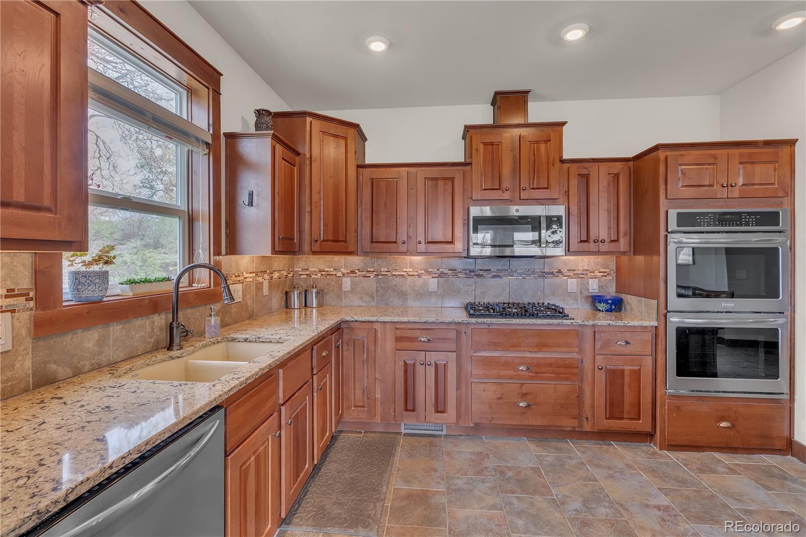 6839 Estes Drive Arvada, CO 80004 - Photo 6 of 34 a kitchen with stainless steel appliances granite countertop wooden cabinets stove top oven and sink