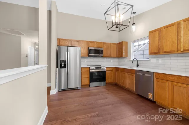 a kitchen with stainless steel appliances granite countertop a refrigerator a sink dishwasher a oven with a dining table and chairs