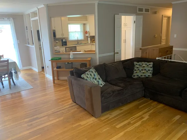 a living room with furniture and a large mirror next to a window