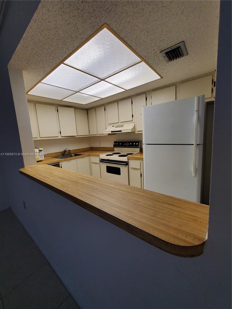 5550 Northwest 44th Street, Unit 111B Lauderhill, FL 33319 - Photo 8 of 22 a kitchen with kitchen island a sink a stove and a refrigerator