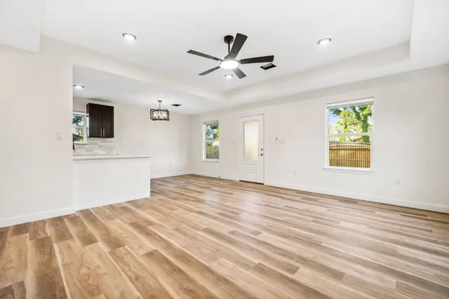 a view of empty room with wooden floor and fan