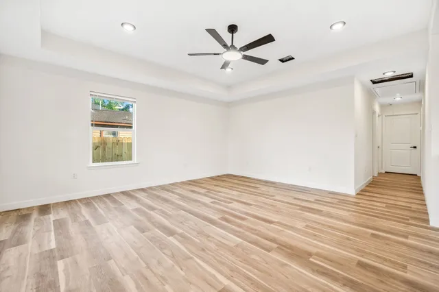an empty room with wooden floor and windows