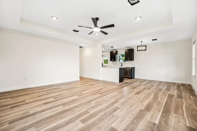 a view of a livingroom with a chandelier fan and wooden floor