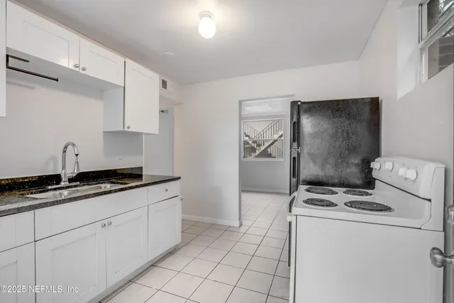 a kitchen with granite countertop a sink a stove a washer and dryer
