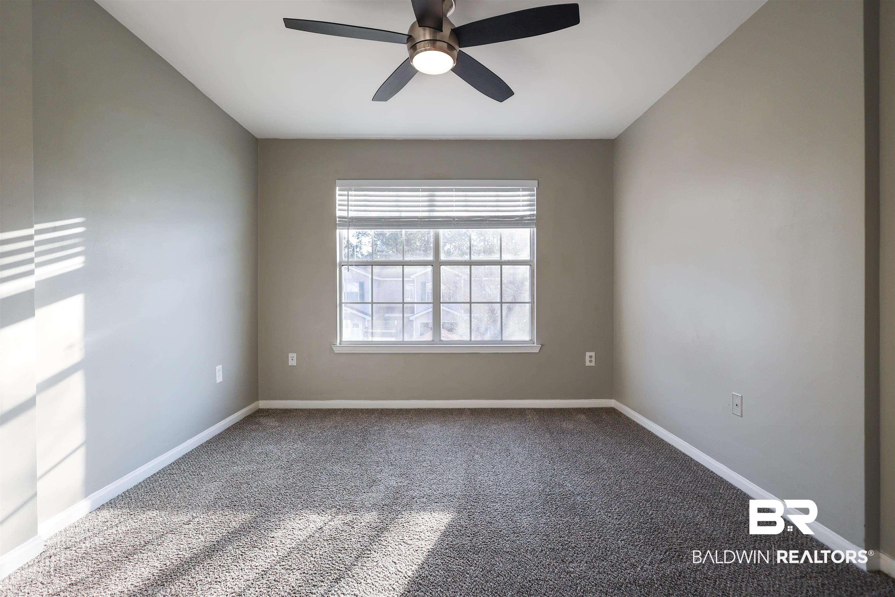 1517 Regency Road, Unit 125 Gulf Shores, AL 36542 - Photo 18 of 26 Carpeted spare room featuring baseboards and a ceiling fan