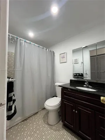 a bathroom with a granite countertop sink a toilet and a mirror