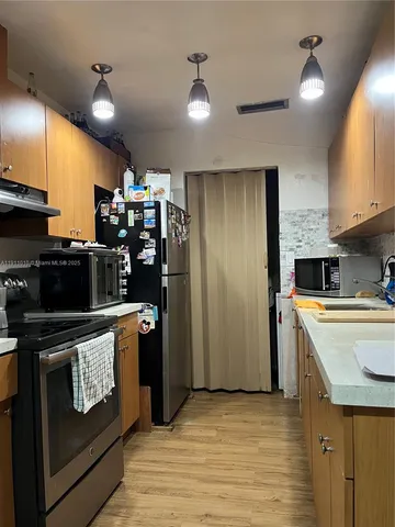 a kitchen with stainless steel appliances granite countertop a refrigerator a stove and a sink