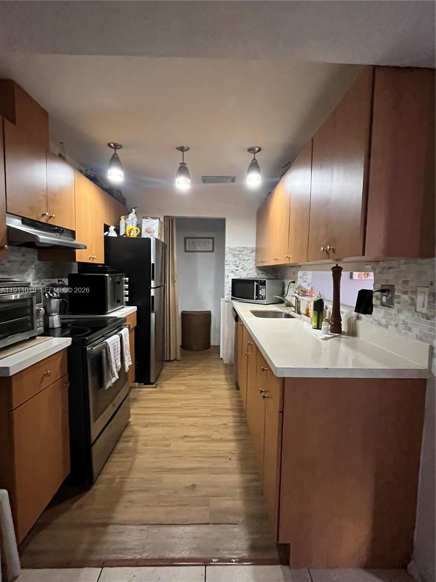 12215 Southwest 119th Terrace Miami, FL 33186 - Photo 5 of 17 a kitchen with stainless steel appliances granite countertop a stove a sink and a refrigerator