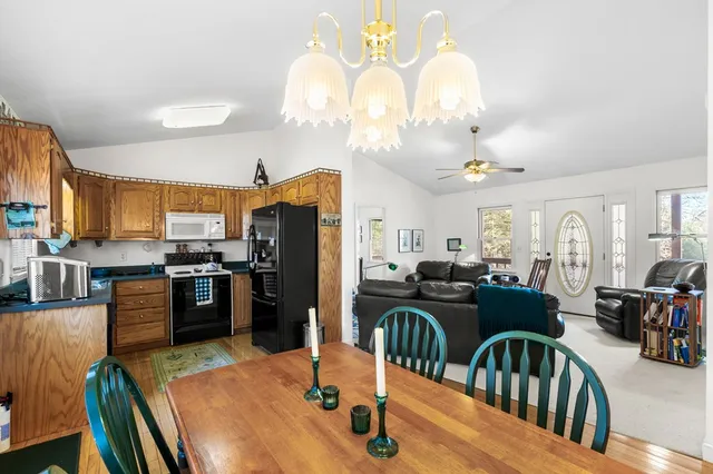 a kitchen with stainless steel appliances kitchen island granite countertop a refrigerator a stove top oven and couches with wooden floor