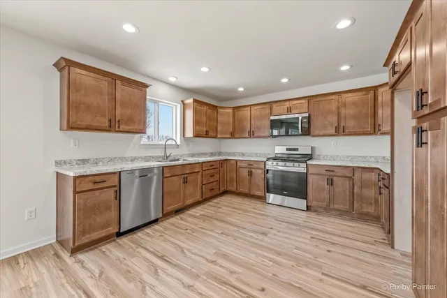 a kitchen with a stove sink cabinets and wooden floor