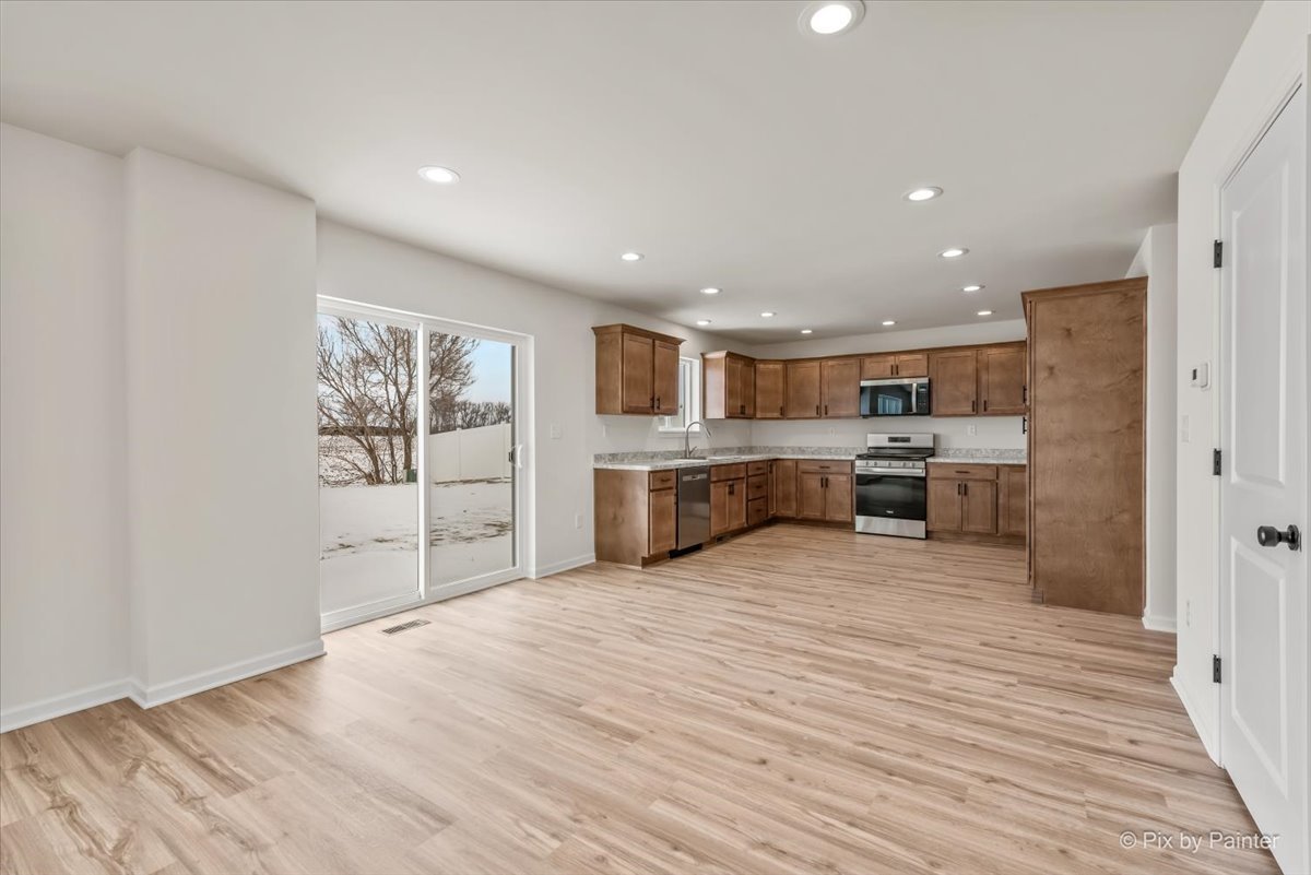 611 Apple Valley Road Harvard, IL 60033 - Photo 7 of 29 a large kitchen with stainless steel appliances kitchen island a large counter top and wooden floors