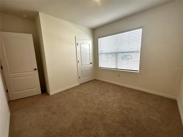 an empty room with windows and refrigerator