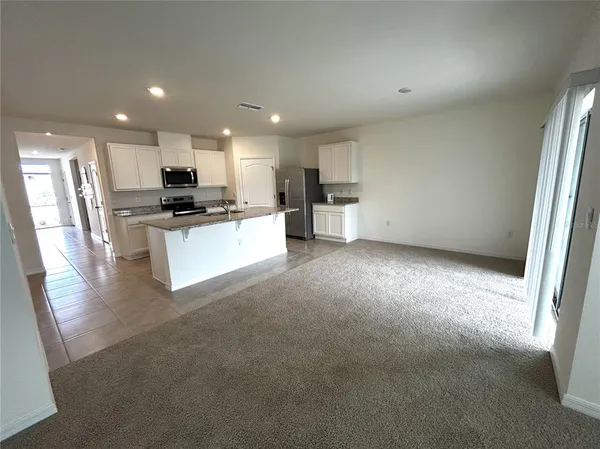 a kitchen with stainless steel appliances a refrigerator a stove a sink a microwave a refrigerator and white cabinets with wooden floor