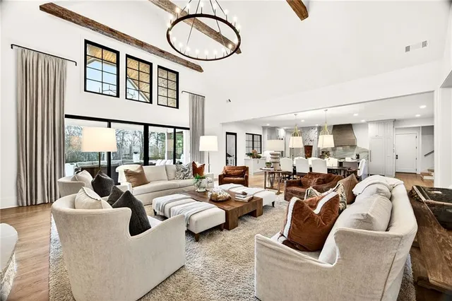 a view of living room kitchen with stainless steel appliances granite countertop lots of white furniture a flat screen tv and a refrigerator
