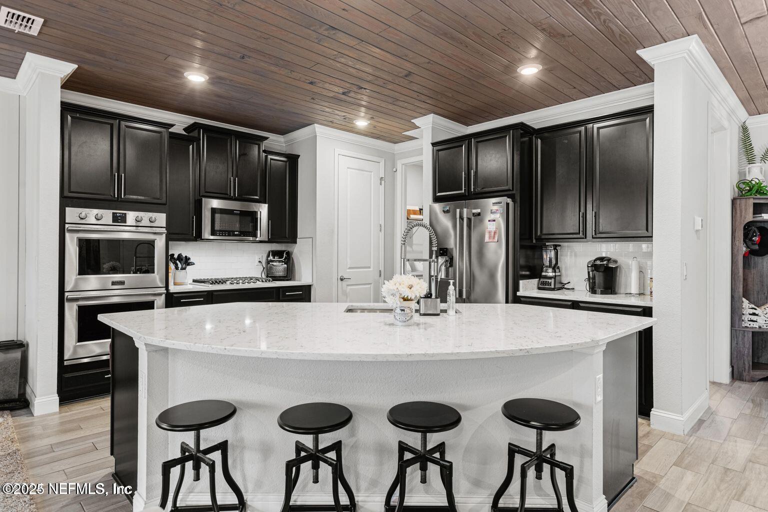 35 Clifton Bay Loop St. Johns, FL 32259 - Photo 8 of 24 a kitchen with stainless steel appliances granite countertop a refrigerator a stove a sink a oven with white cabinets and chairs