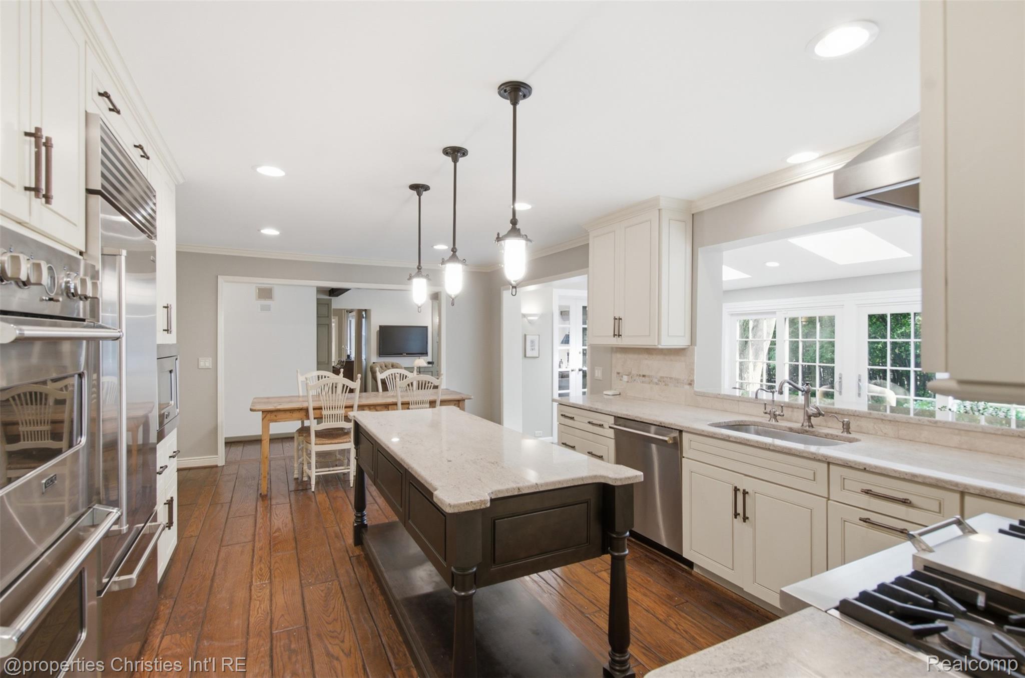 25235 Canterbury Road Franklin, MI 48025 - Photo 17 of 56 Gourmet kitchen featuring a central island with a light-toned countertop, stainless steel appliances, wood-finish flooring, recessed lighting, and custom cabinetry