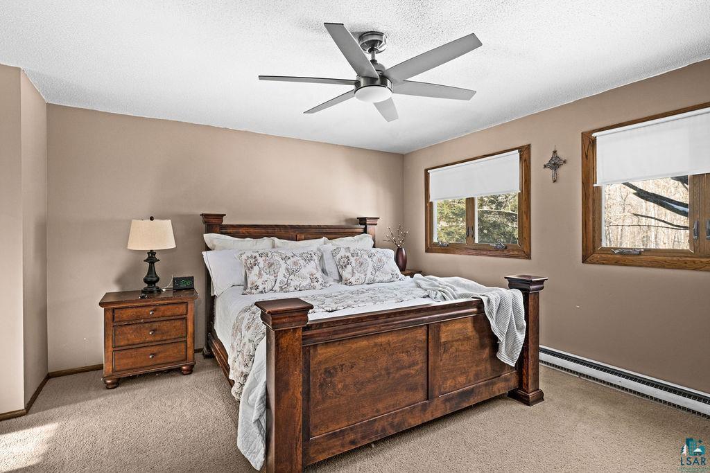 421 St Louis River Road Proctor, MN 55810 - Photo 12 of 57 Bedroom with light carpet, a ceiling fan, a baseboard heating unit, and a textured ceiling