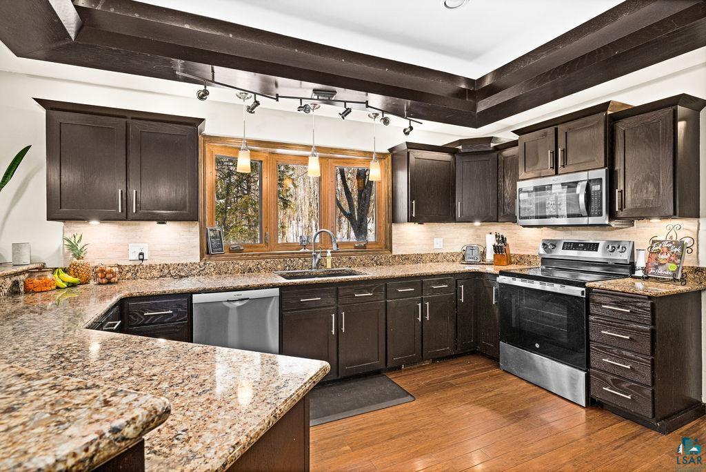421 St Louis River Road Proctor, MN 55810 - Photo 21 of 57 Kitchen featuring light stone countertops, dark wood finish cabinetry, stainless steel appliances, dark wood-type flooring, and backsplash