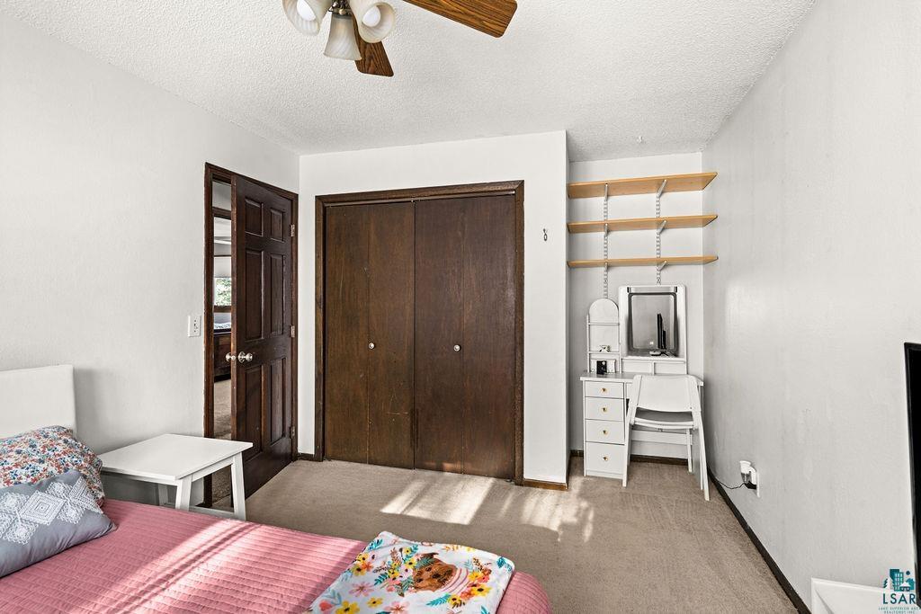 421 St Louis River Road Proctor, MN 55810 - Photo 41 of 57 Bedroom with a closet, light colored carpet, a textured ceiling, and ceiling fan