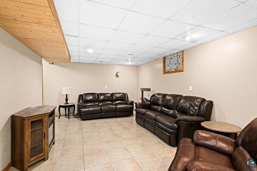 421 St Louis River Road Proctor, MN 55810 - Photo 44 of 57 Living area featuring a drop ceiling, light tile patterned floors, and a textured wall