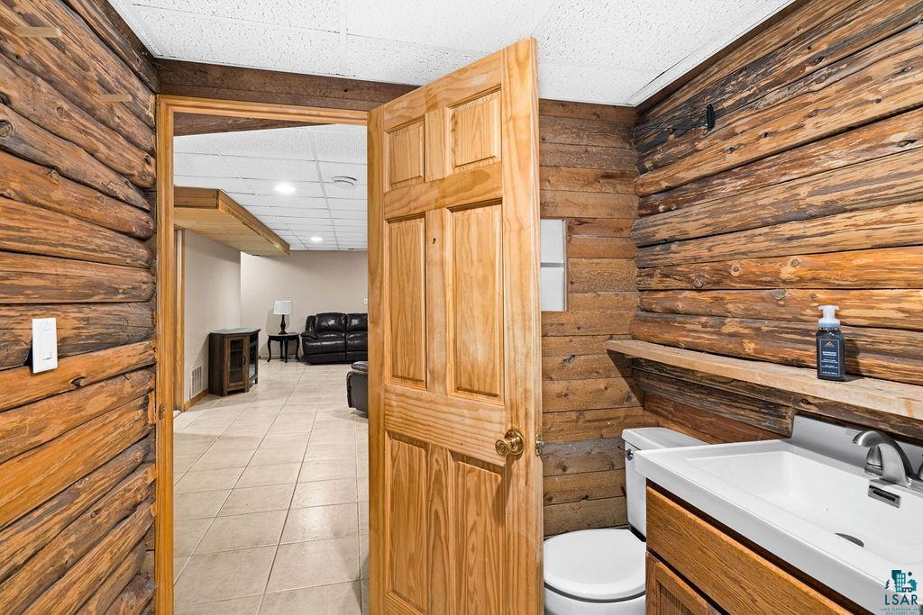 421 St Louis River Road Proctor, MN 55810 - Photo 50 of 57 Bathroom with vanity, light tile patterned floors, a drop ceiling, and rustic walls