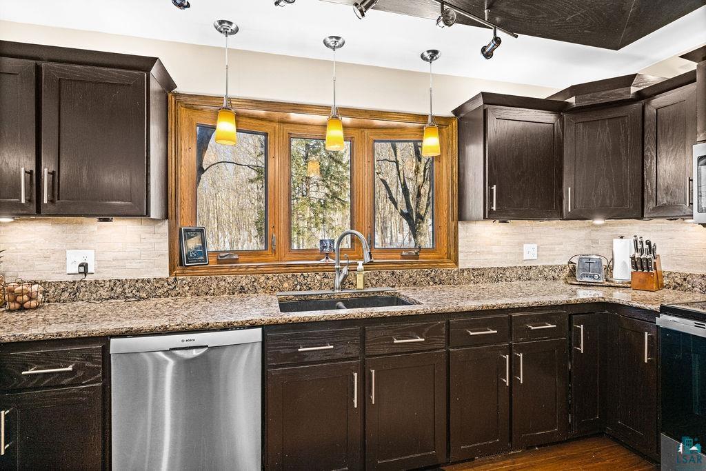 421 St Louis River Road Proctor, MN 55810 - Photo 5 of 57 Kitchen featuring dark wood finish cabinets, stainless steel appliances, tasteful backsplash, and light stone countertops