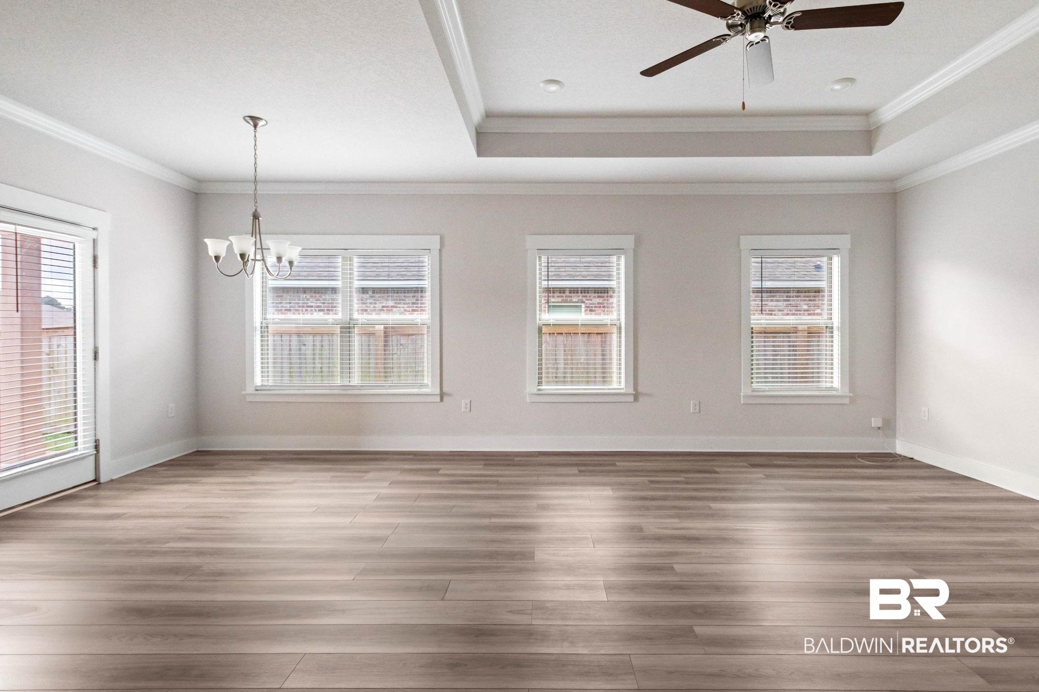 1710 Grouse Street Foley, AL 36535 - Photo 22 of 76 Spacious room featuring wood-finish flooring, three windows with blinds, a single-pane glass door, and a tray ceiling with a ceiling fan