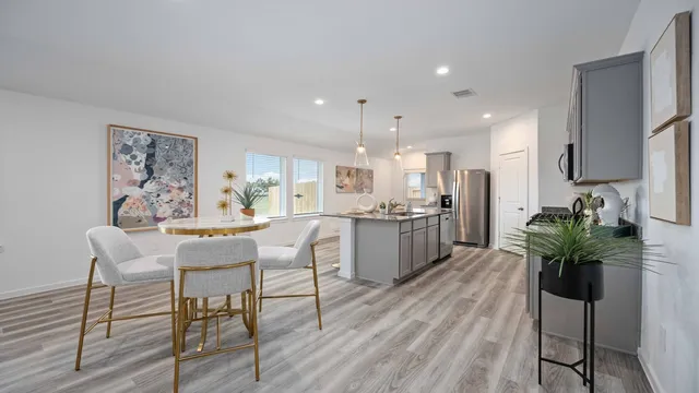 a dining room with furniture a potted plant and kitchen view