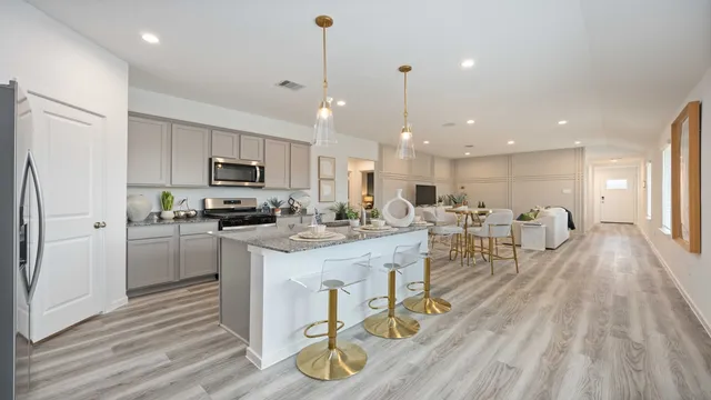 a kitchen with stainless steel appliances granite countertop a refrigerator a stove top oven a sink dishwasher and white cabinets with wooden floor