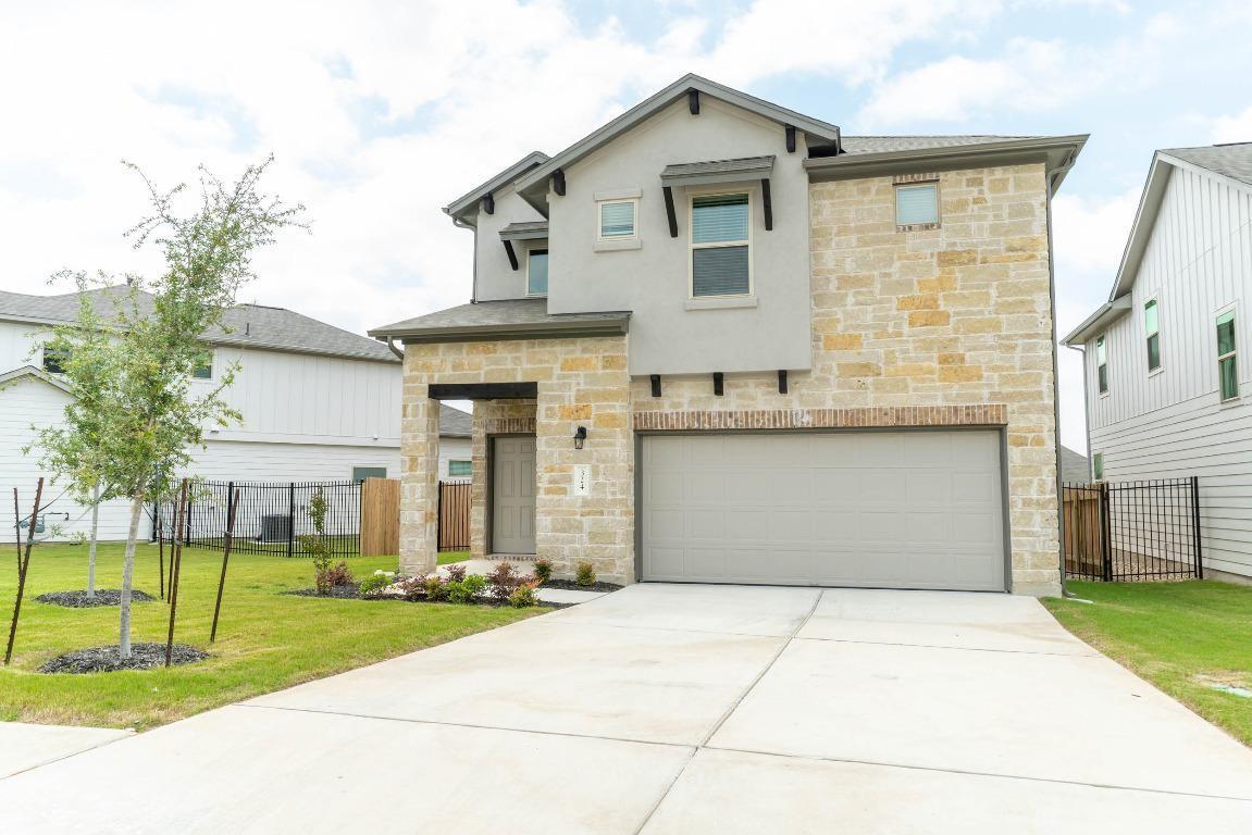 View of front facade featuring stone siding, an attached garage, and driveway
