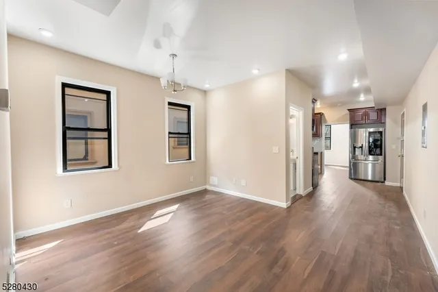 a view of a big room with wooden floor and a kitchen
