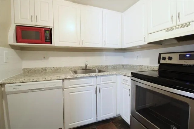 a kitchen with granite countertop white cabinets stainless steel appliances and sink