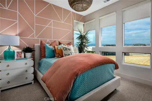 a bedroom with bed and a lamp on dresser