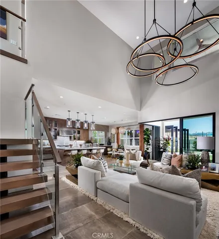 a living room with furniture kitchen view and a chandelier
