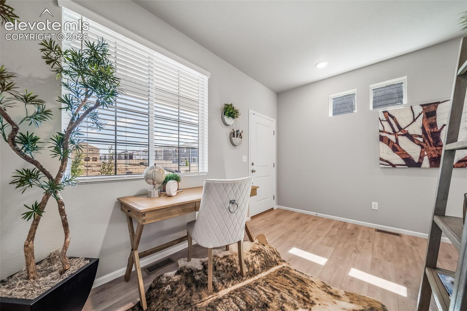 4866 Truscott Road Colorado Springs, CO 80925 - Photo 11 of 20 Bright room featuring a large window with blinds, light wood-finish flooring, recessed lighting, and two high transom windows
*Photos of a model home*