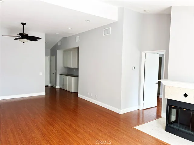 a view of an empty room with wooden floor and a fireplace