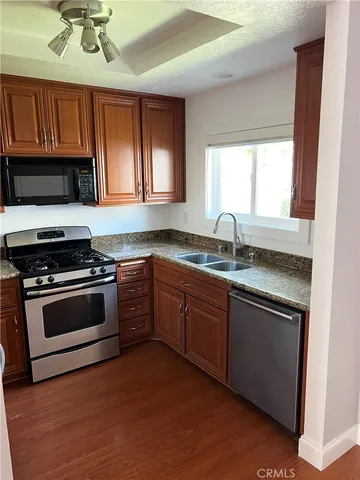 a kitchen with granite countertop wooden cabinets a sink and a stove