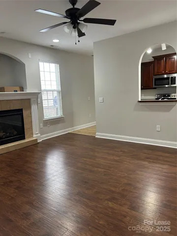 an empty room with wooden floor fireplace and windows