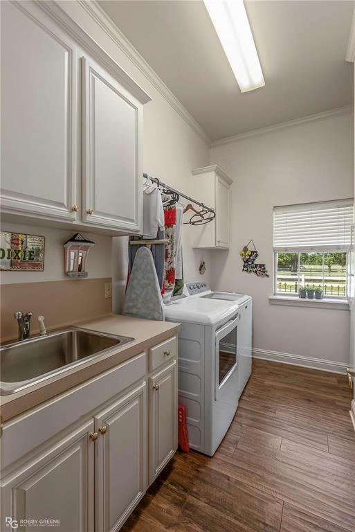 1171 Wemple Road Bossier City, LA 71111 - Photo 18 of 31 Washroom with crown molding, dark wood-type flooring, cabinet space, and washing machine and clothes dryer
