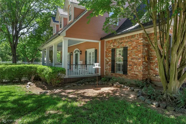 a view of a brick house with a small yard and a large tree