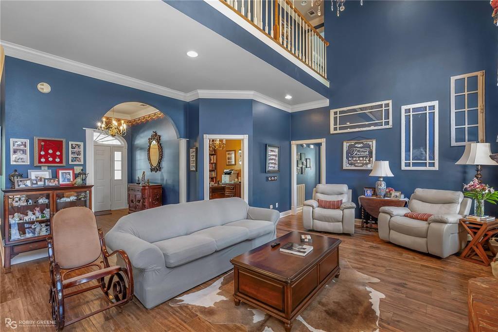 1171 Wemple Road Bossier City, LA 71111 - Photo 6 of 31 Living room with crown molding, wood finished floors, a high ceiling, arched walkways, and a chandelier