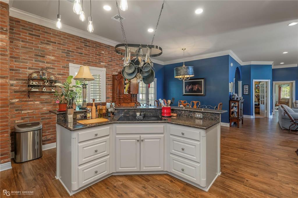 1171 Wemple Road Bossier City, LA 71111 - Photo 31 of 31 Kitchen featuring white cabinetry, dark stone countertops, crown molding, open floor plan, and brick wall