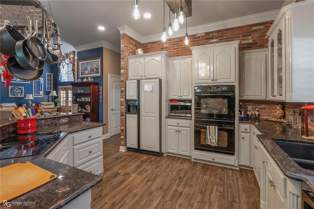 1171 Wemple Road Bossier City, LA 71111 - Photo 8 of 31 Kitchen with brick wall, ornamental molding, black appliances, glass insert cabinets, and dark wood-type flooring